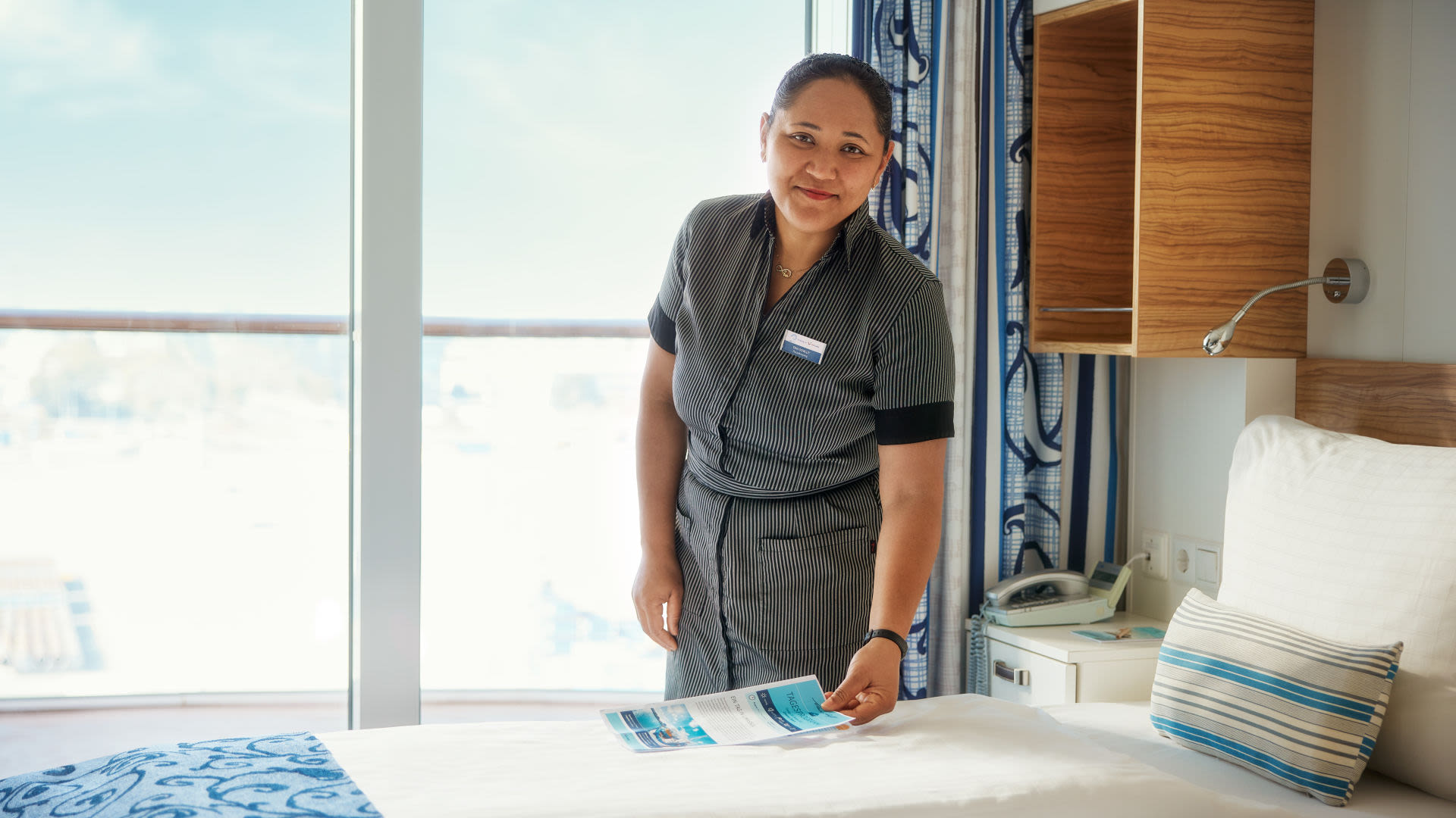 Frau richtet Bett in Kreuzfahrtschiffkabine der Mein Schiff® Flotte.