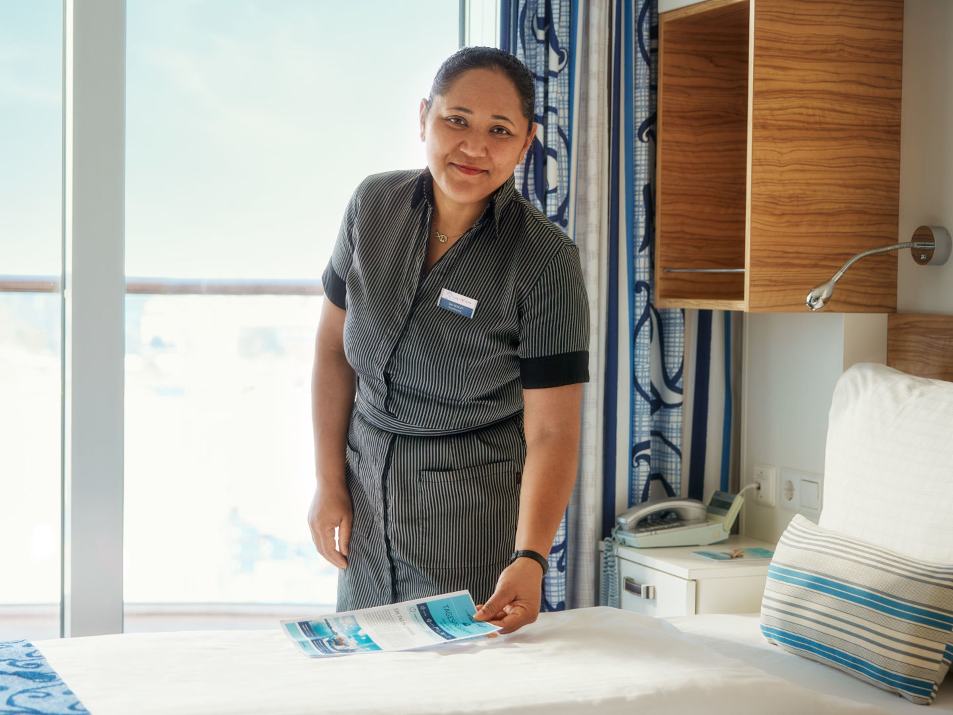 Kabinen-Service Frau richtet Bett in Kreuzfahrtschiffkabine der Mein Schiff® Flotte.