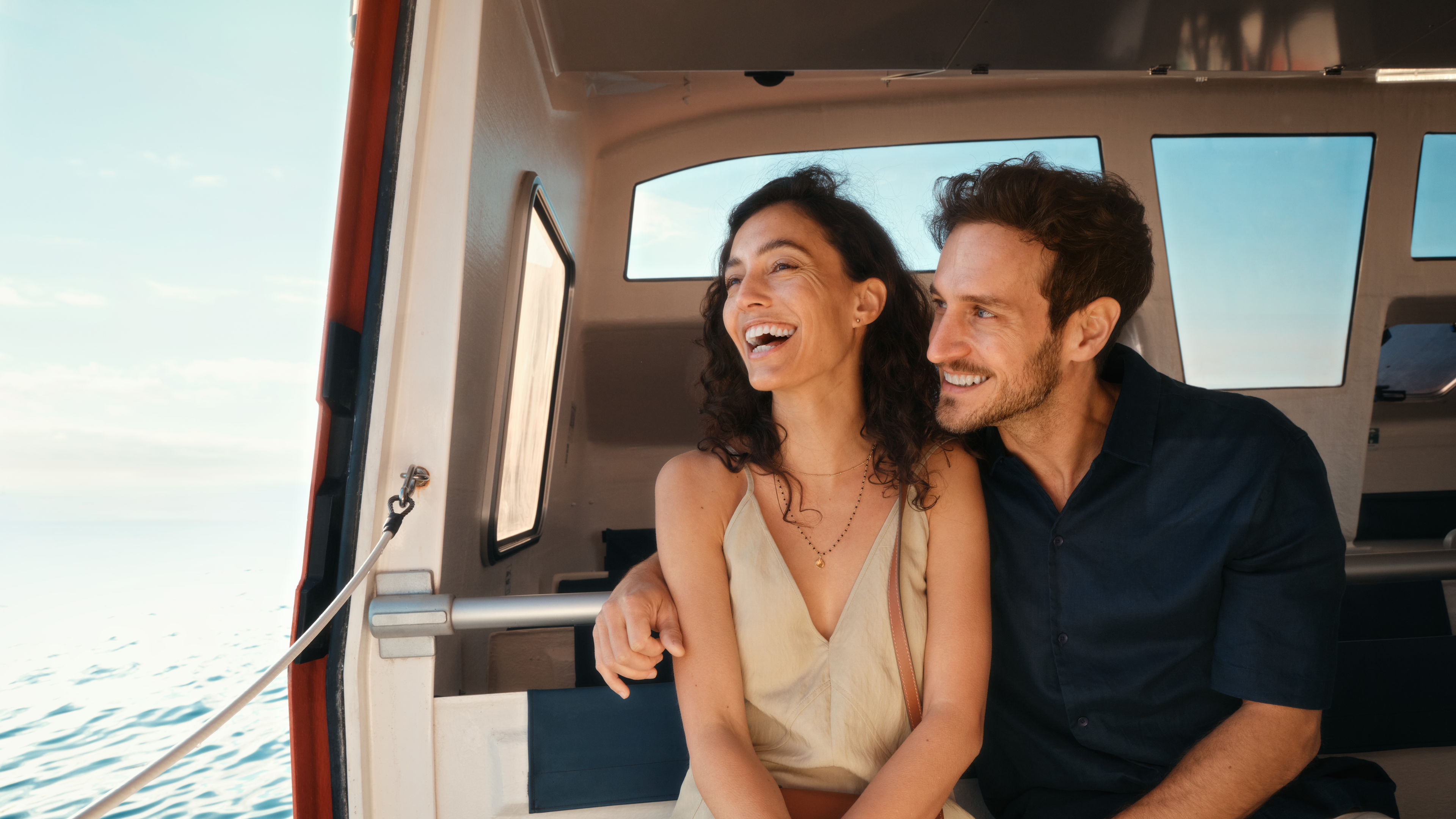 Lachendes Paar auf Boot, sonniger Tag, blaues Meer.