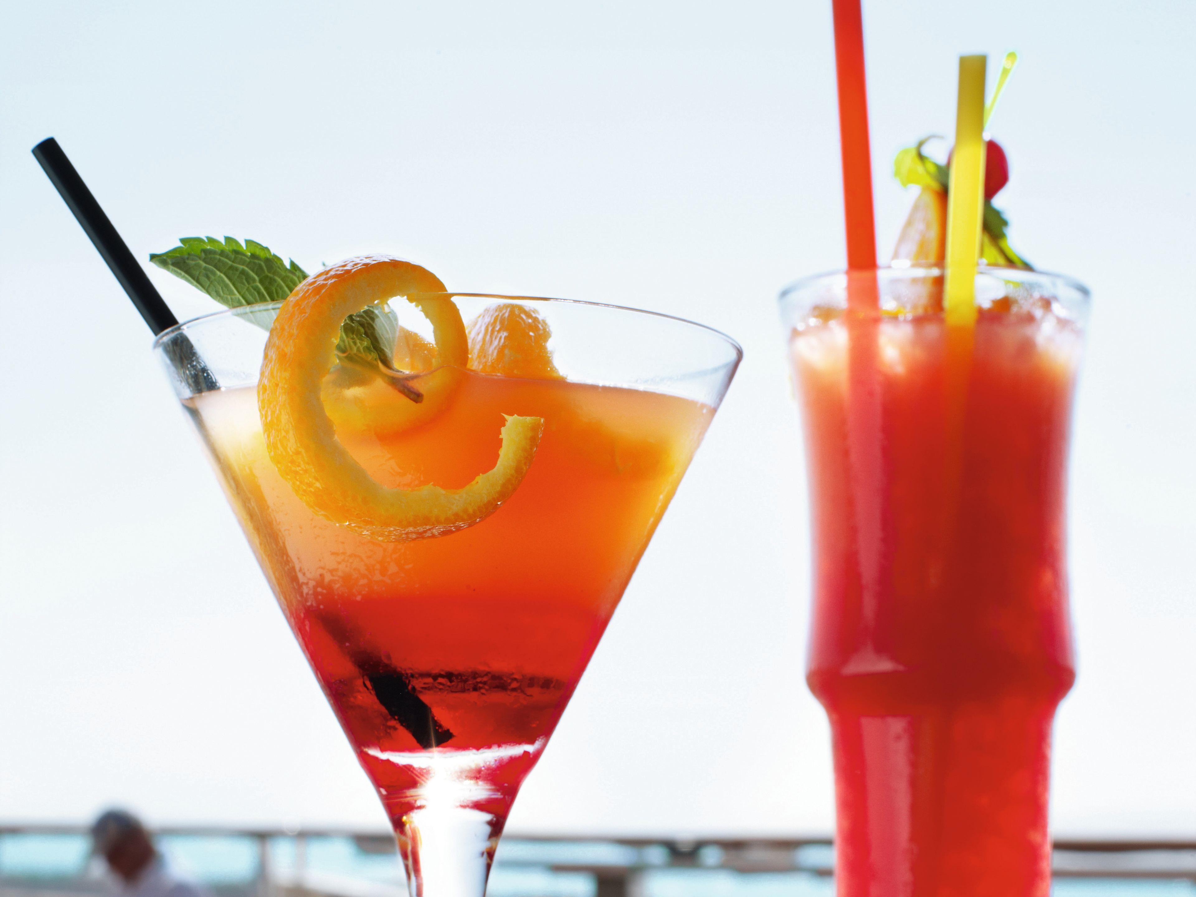 Zwei bunte Cocktails mit Strohhalmen vor blauem Himmel. Zwei bunte Cocktails mit Strohhalmen vor blauem Himmel.