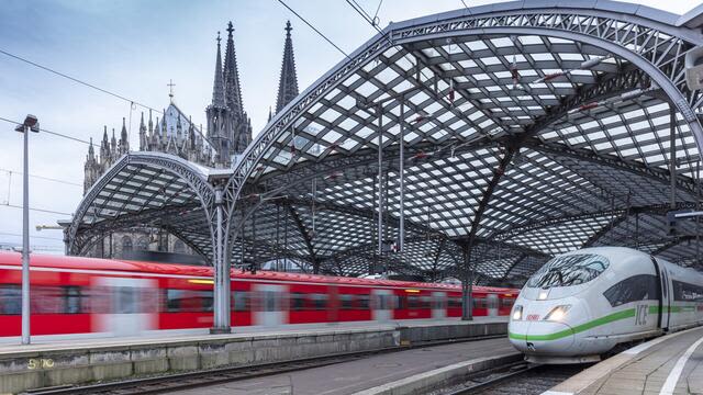 Kölner Dom, ICE-Zug und rote Regionalbahn am Bahnhof.