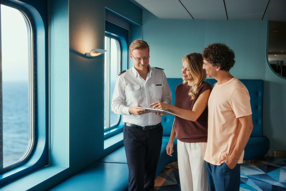 Drei Personen auf Kreuzfahrtschiff, Meerblick durch Fenster.