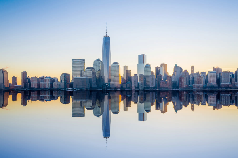 New York Skyline bei Sonnenaufgang, Spiegelung im Wasser.