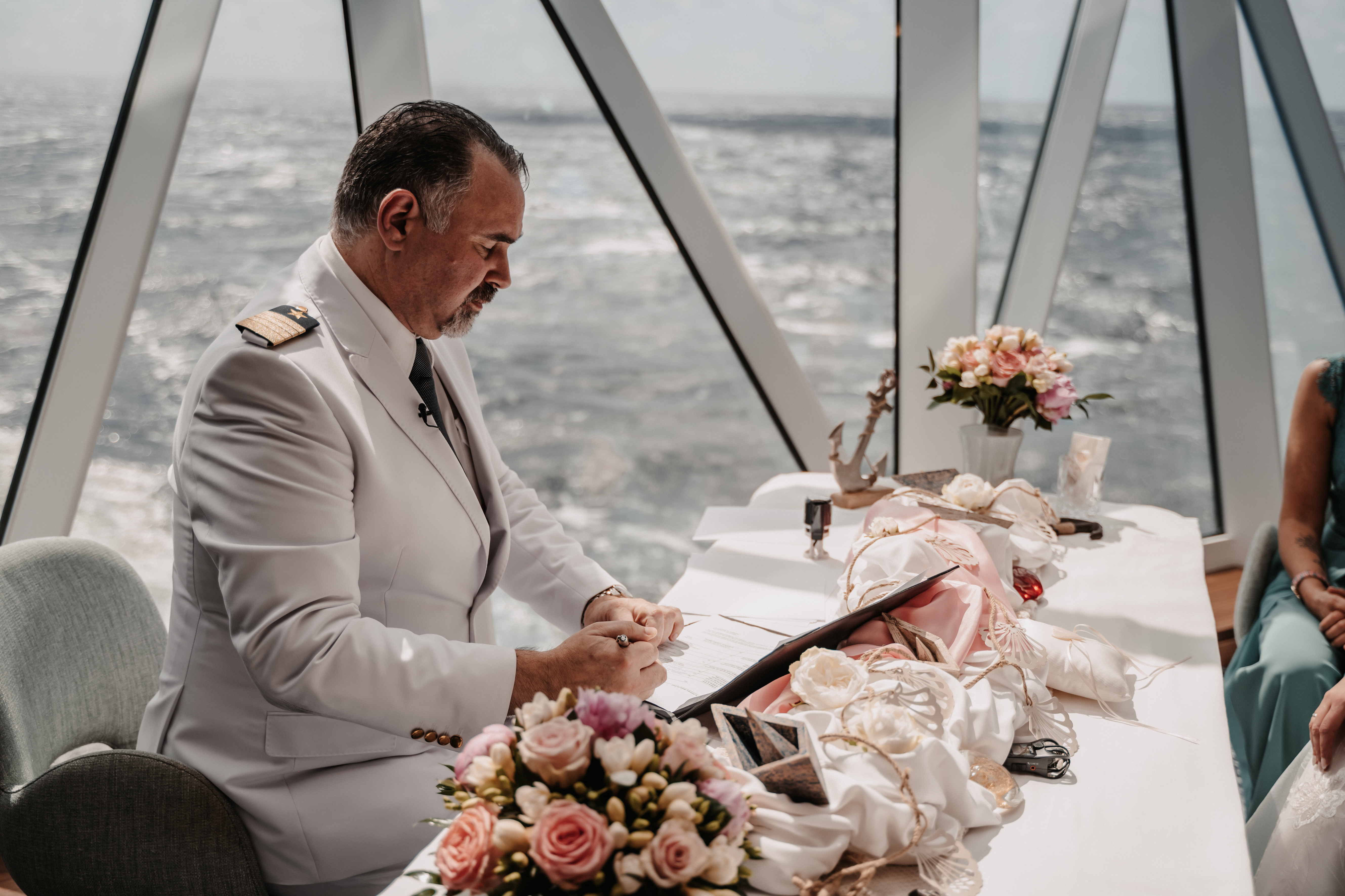 Kapitän in weißer Uniform bei Hochzeit auf Kreuzfahrtschiff, Blumenarrangement.