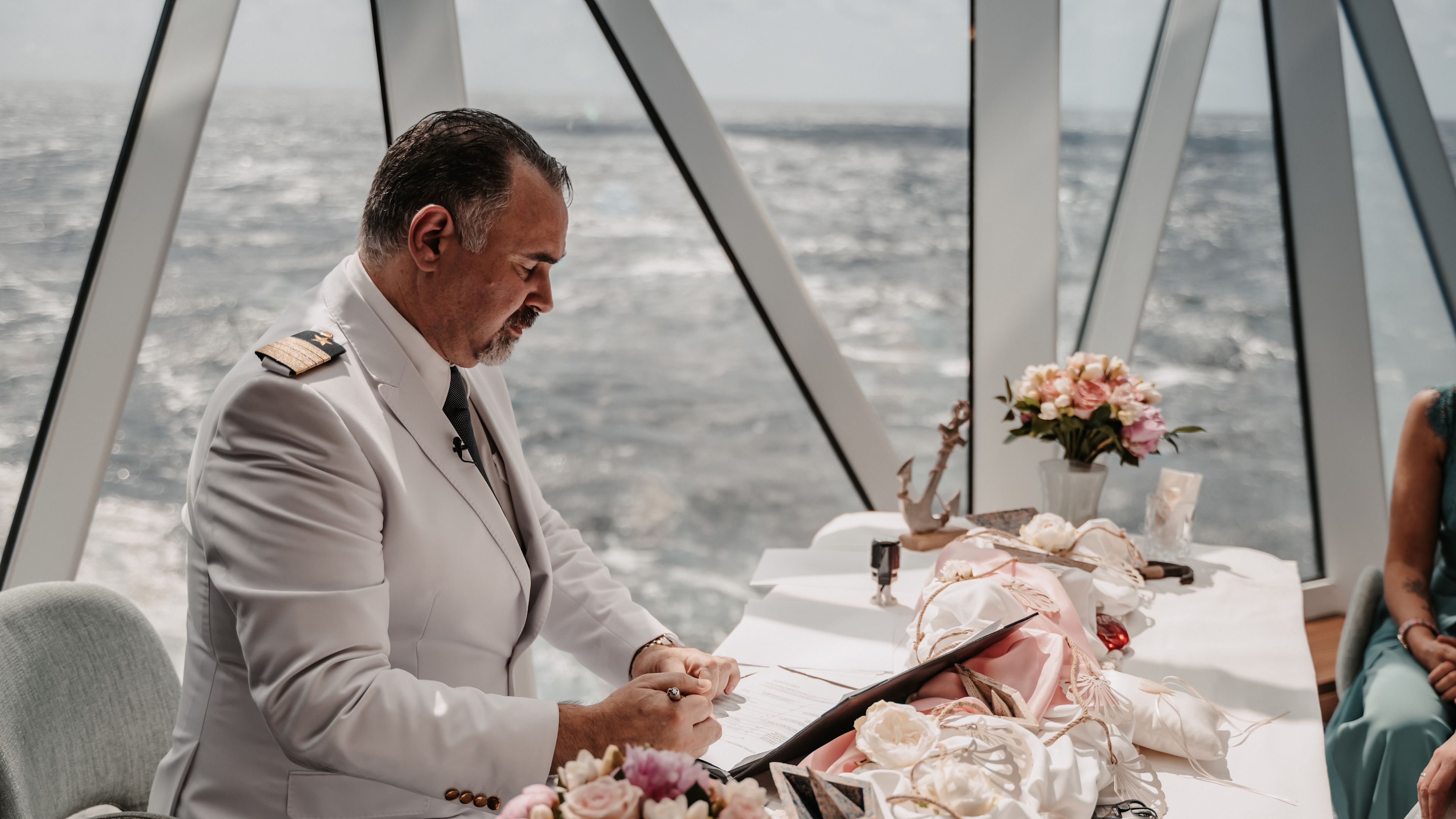 Trauung an Bord Kapitän in weißer Uniform bei Hochzeit auf Kreuzfahrtschiff, Blumenarrangement.