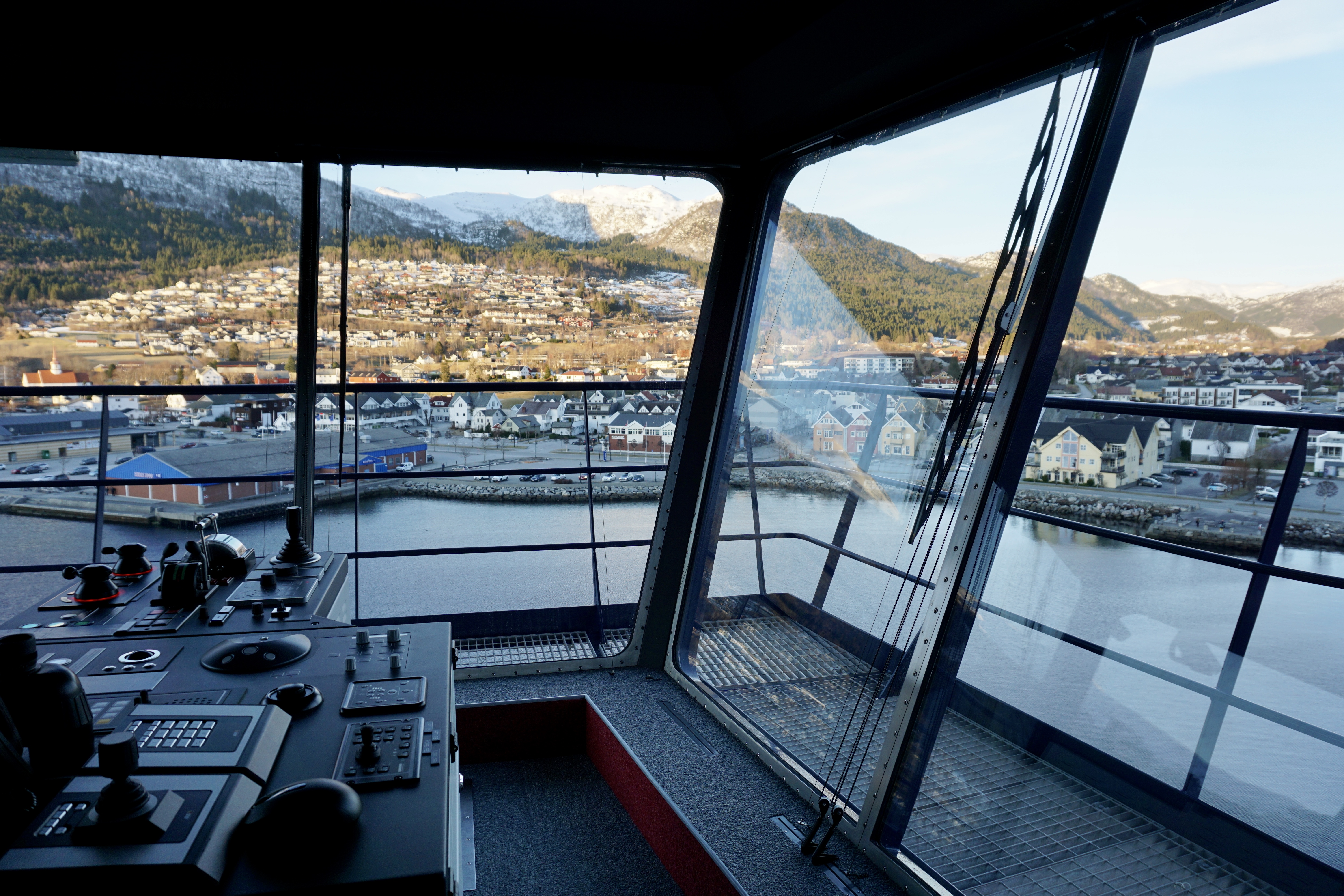 Blick aus der Brücke eines Kreuzfahrtschiffs auf norwegische Küstenstadt.