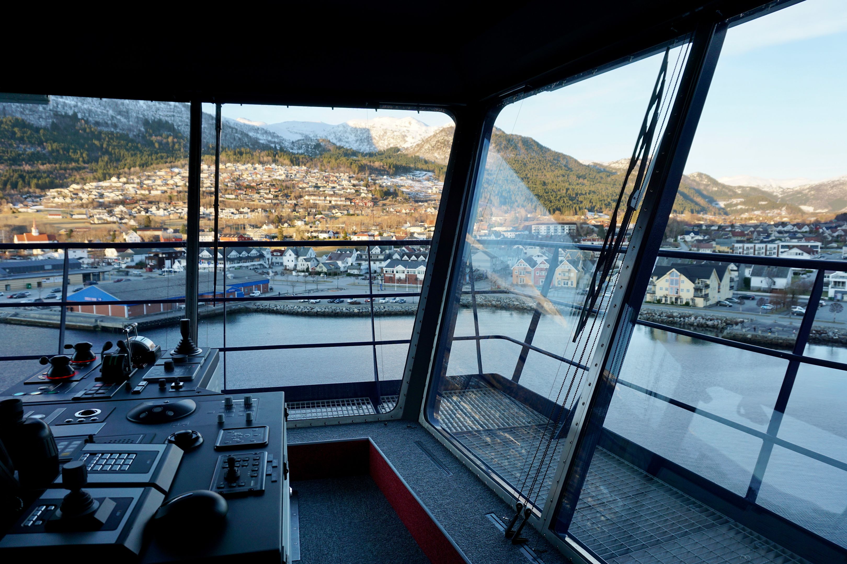 Blick aus der Brücke eines Kreuzfahrtschiffs auf norwegische Küstenstadt.
