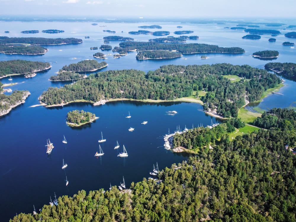 Segelboote im Archipel von Stockholm, umgeben von grünen Inseln.