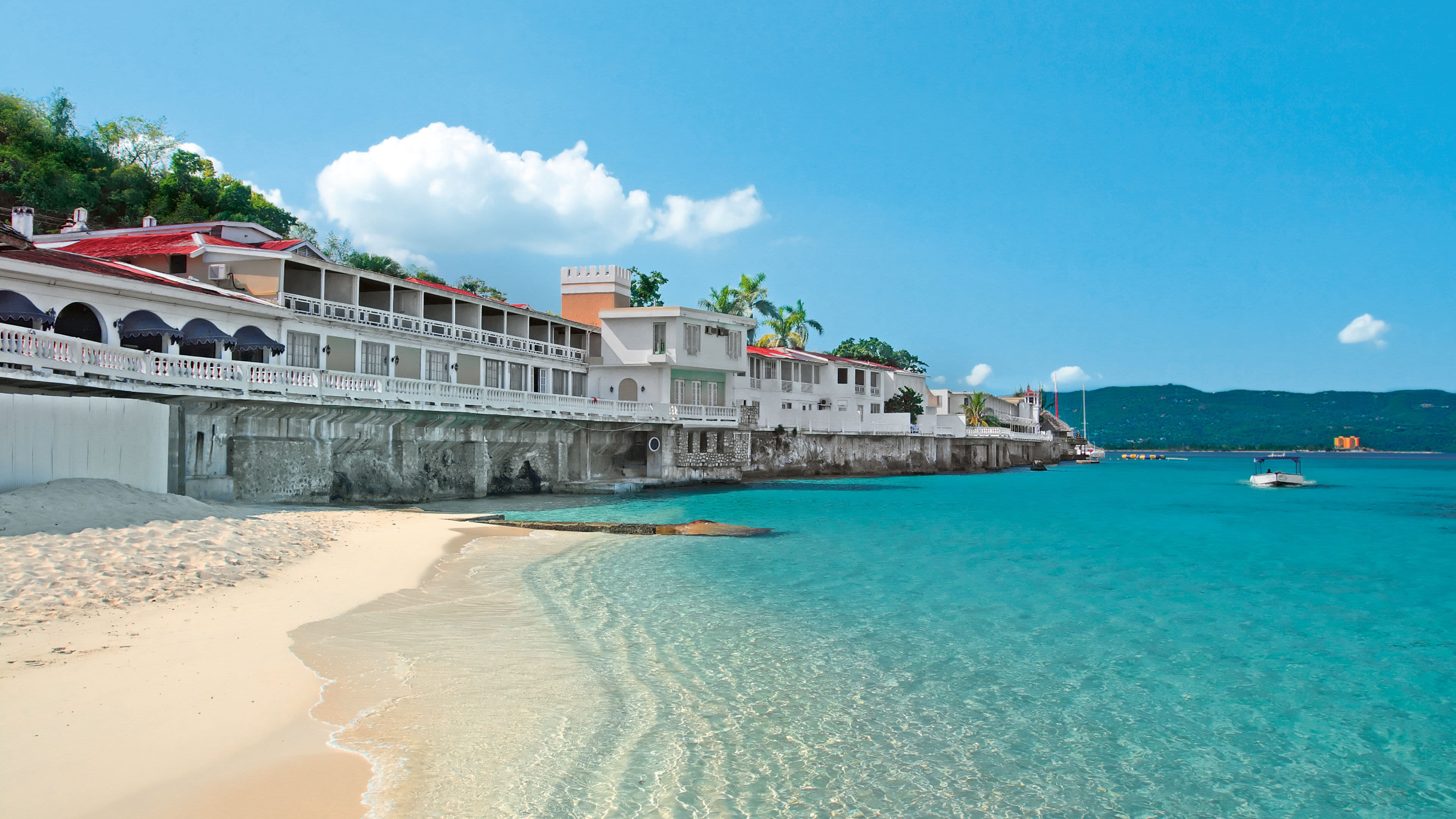 Mittelamerika Jamaika Montego Bay Strand mit türkisfarbenem Wasser, weißen Gebäuden und Booten.