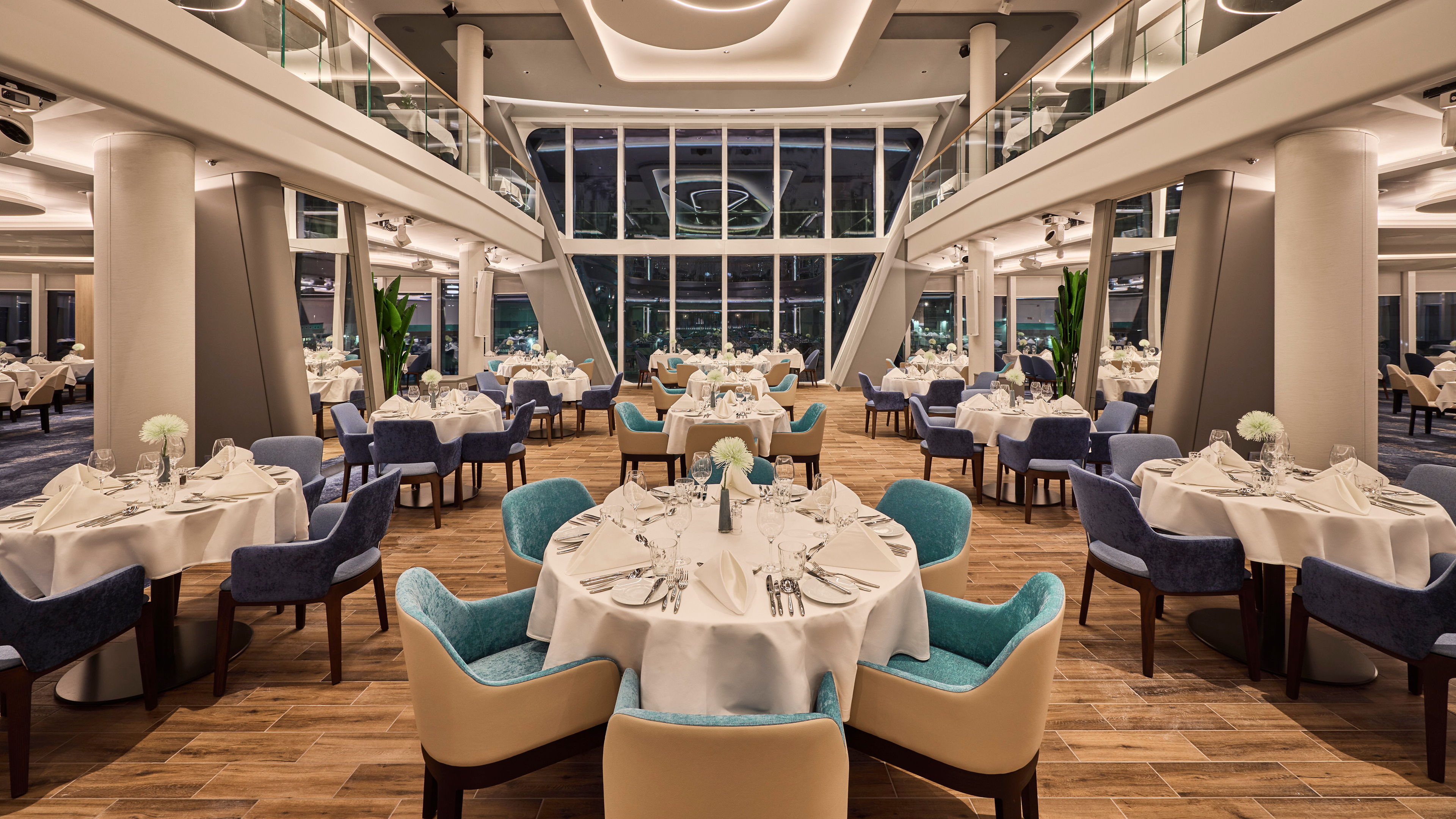 Elegantes Restaurant mit gedeckten Tischen und blauen Stühlen auf Kreuzfahrtschiff.