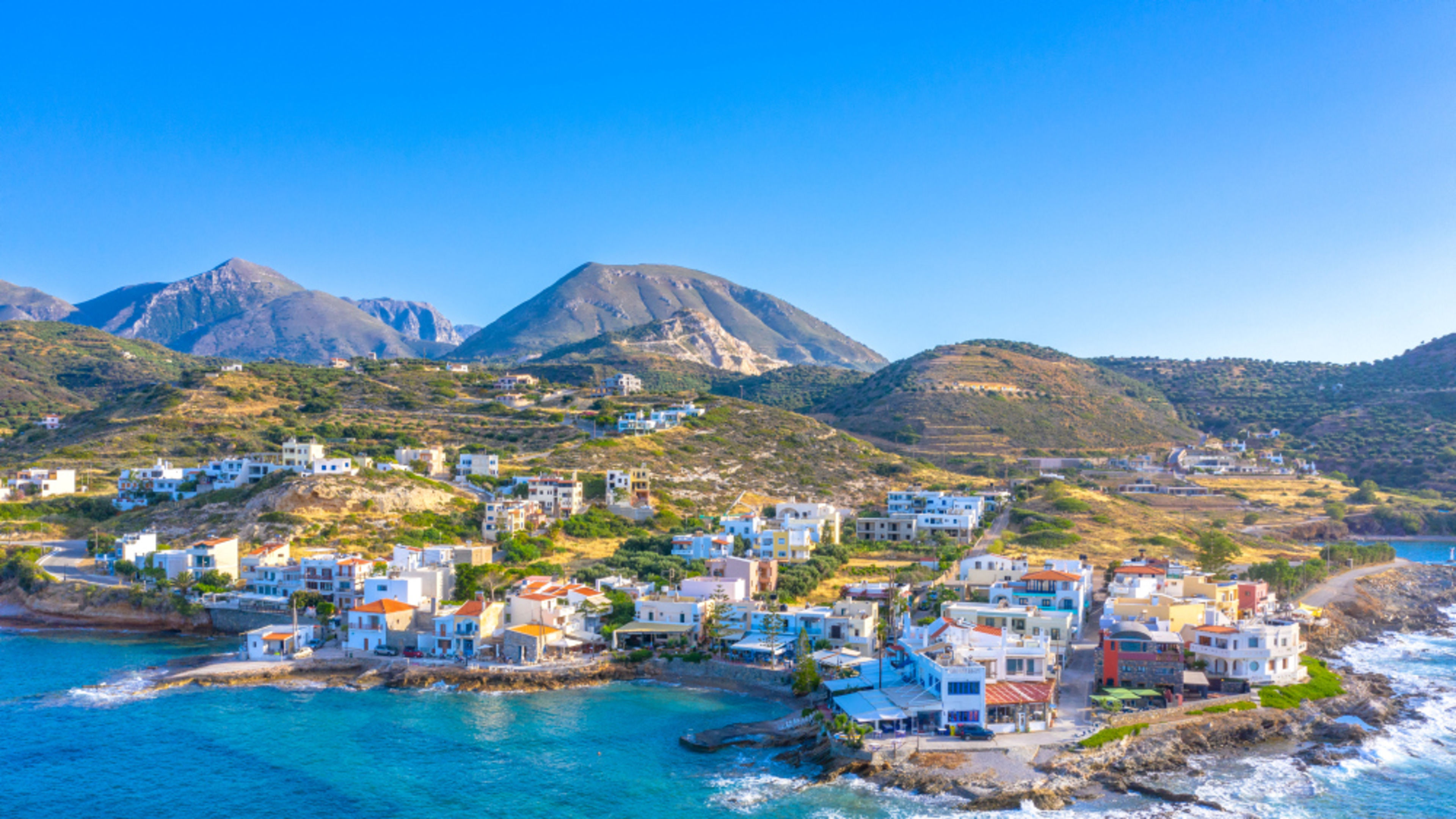 Mittelmeer Kreta Küstenstadt auf Kreta mit bunten Häusern und Bergen im Hintergrund.