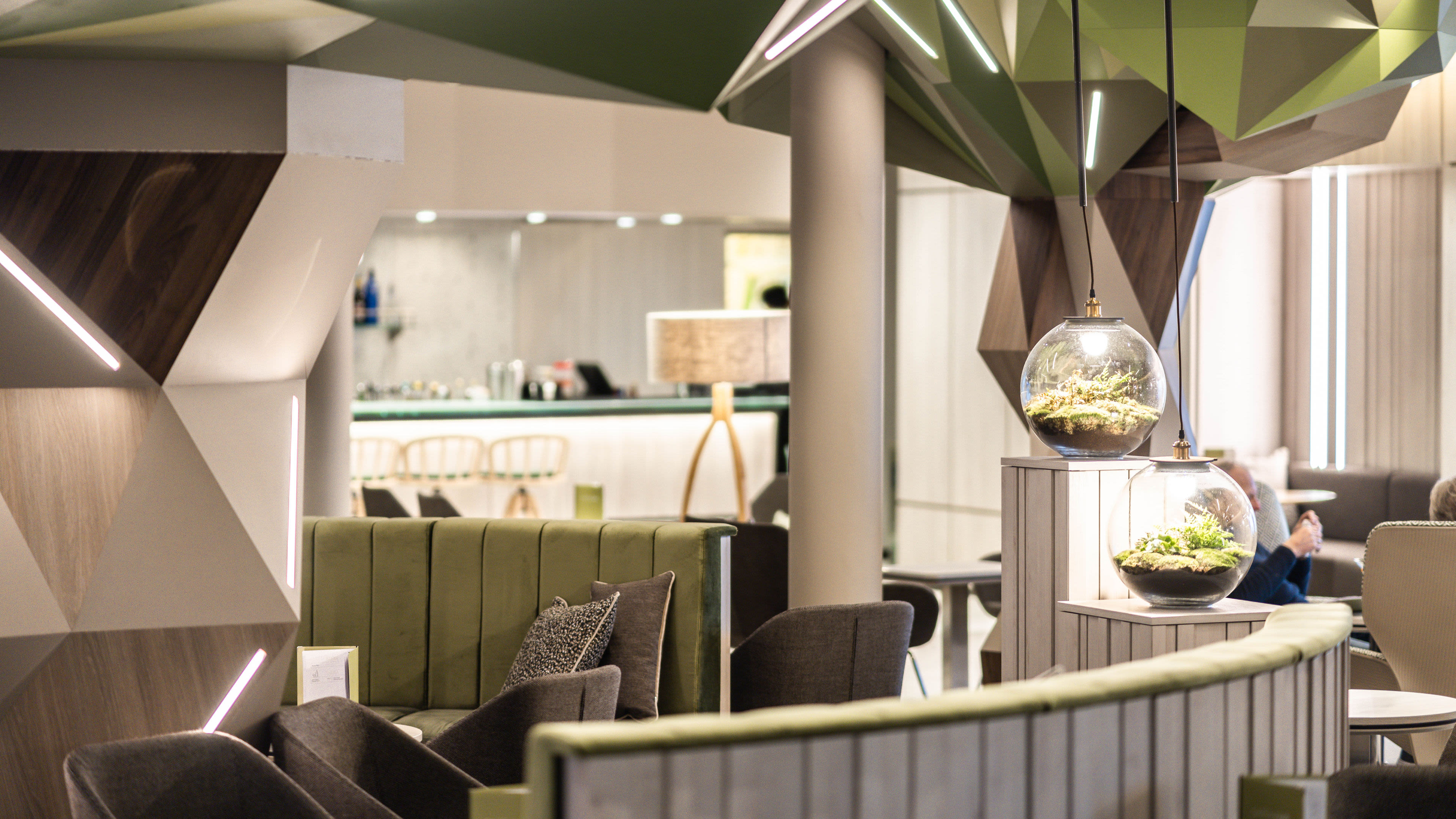 Moderne Lounge mit grünen Pflanzen, geometrischen Formen und gemütlichen Sitzgelegenheiten.