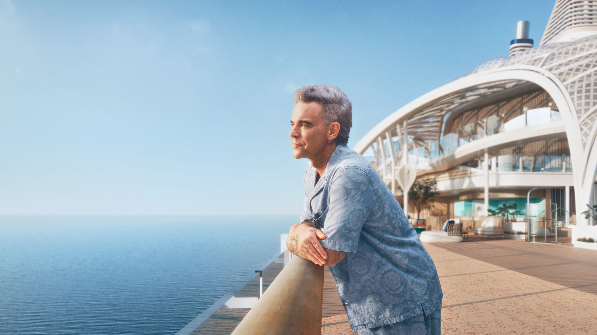 Mann in blauem Hemd lehnt an Kreuzfahrtschiff-Geländer, Meerblick.