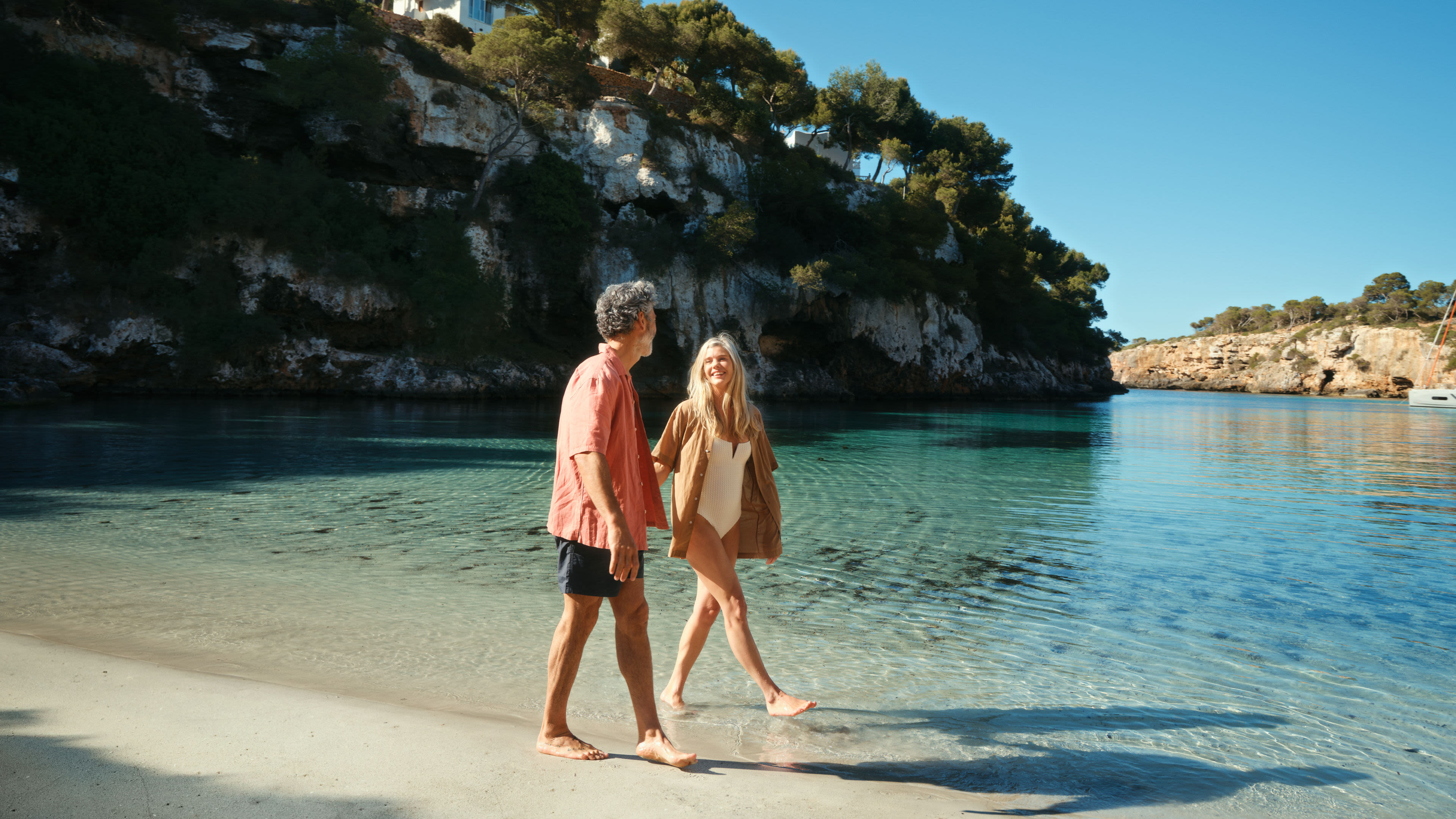 Paar spaziert am Strand von Mallorca, sonniger Tag.
