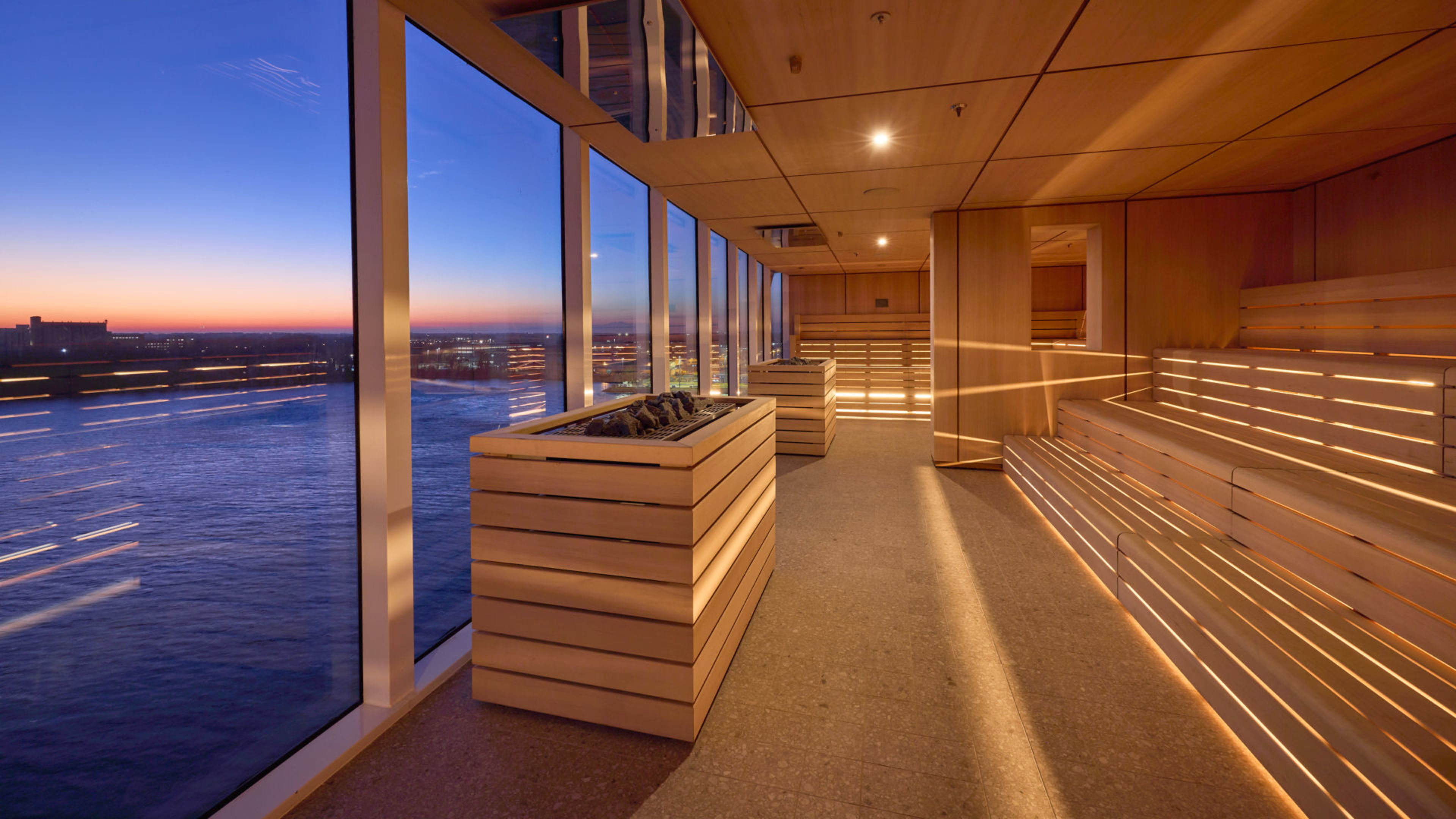 Finnische Horizontsauna im SPA & Meer auf der Mein Schiff Relax Sauna mit Panoramafenster, Blick auf Fluss bei Sonnenuntergang.