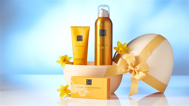 Geschenkset mit gelben Rituals-Produkten und Blumen auf blauem Hintergrund.