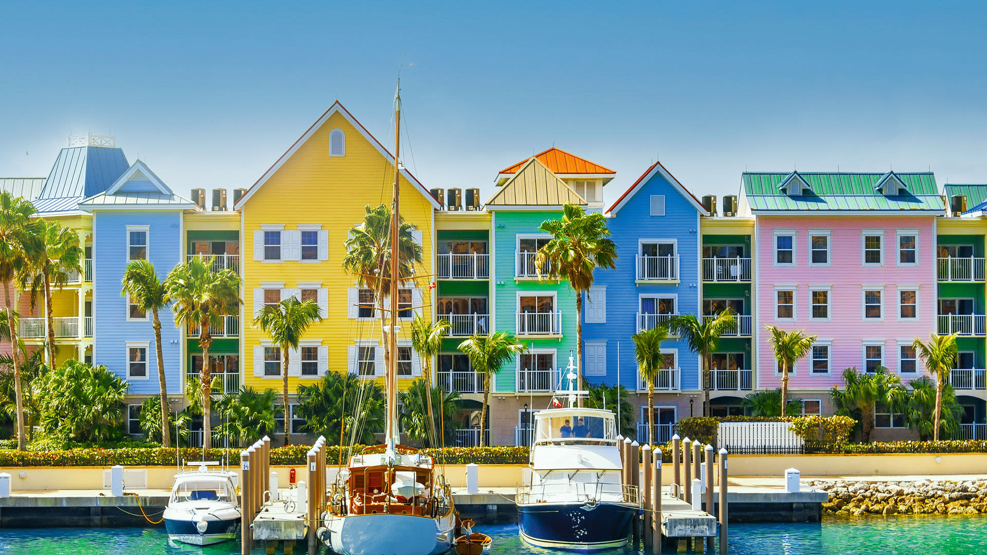 Bunte Häuser und Boote am Hafen, Palmen, blauer Himmel. Bunte Häuser und Boote am Hafen, Palmen, blauer Himmel.