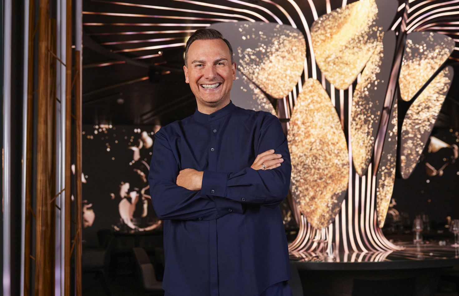 Tim Raue vor einem goldenen Hintergrund