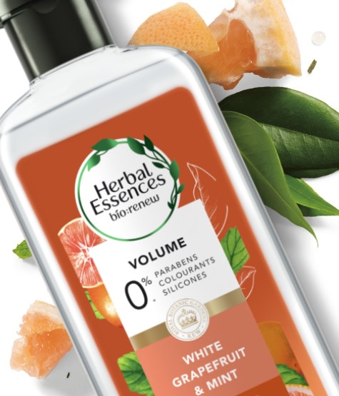 Herbal Essences Grapefruit & Mint Shampoo bottle laying on a bunch of sliced grapefruits and mint leaves