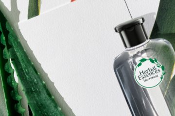 Herbal Essences product bottle on a blank paper next to aloe vera plant leaf