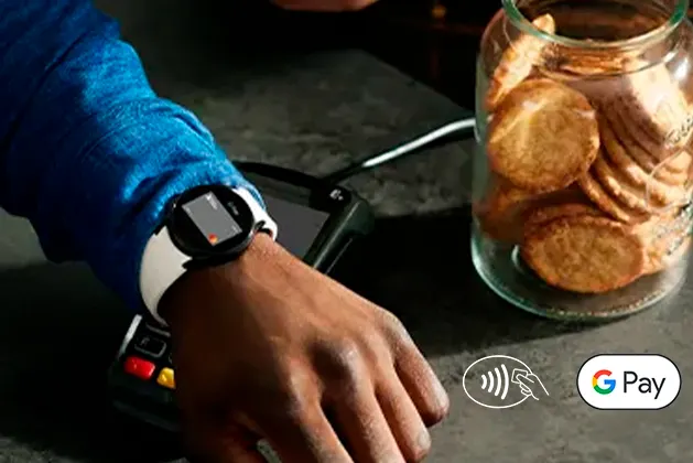 Foto de persona pagando  con su smartt watch y la billetera de Google. En la fotto aparece los  íconos de Pago sin Contacto y de GPay