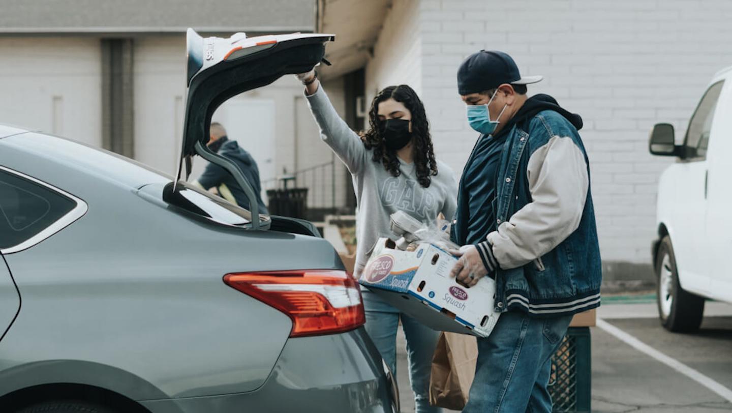 people in masks loading supplies into car