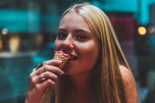 young blonde woman enjoying a strawberry ice cream cone