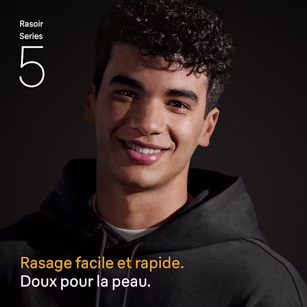 Jeune homme souriant aux cheveux noirs bouclés portant un sweat à capuche noir.