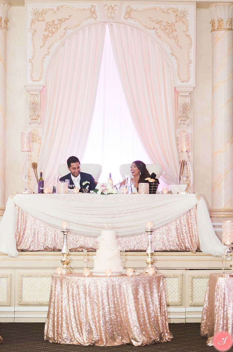 The happy couple smiling at the wedding's head table.