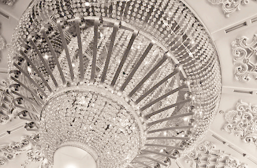 A close-up of the ceiling's white chandelier covered with clear crystals.