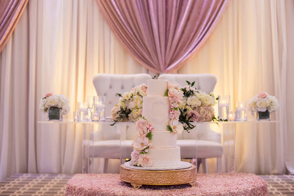 A wedding cake in front of the head table at a wedding.