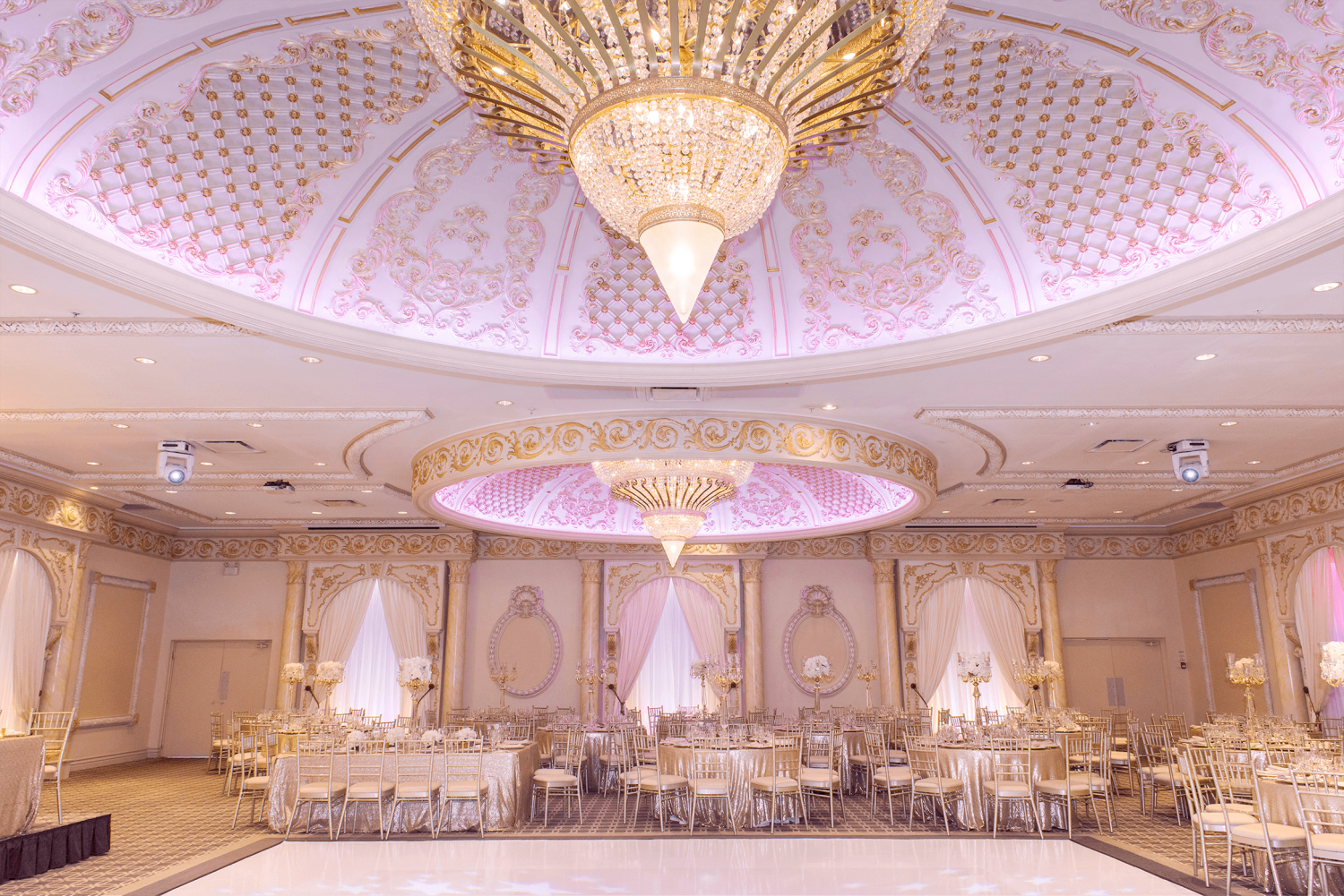 The Classic Ballroom venue at Paradise Banquet Halls with a dance floor below three large chandeliers.