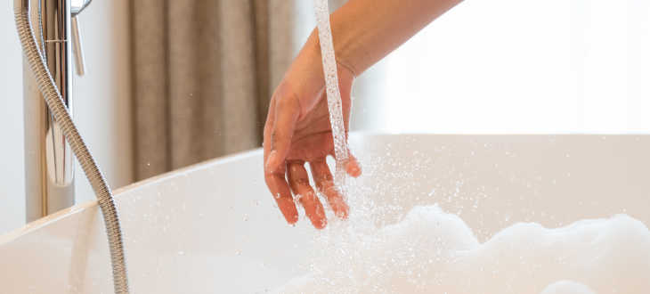 Person bereitet sich auf Dusche/Bad vor und liest Etikett von Shampoo