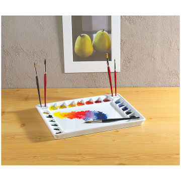 Tom Lynch Porcelain Palette shown on table with wells filled with paint, and brushes stored