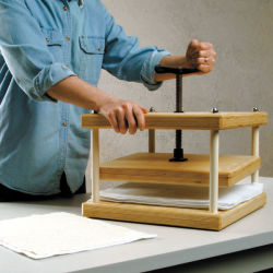 Arnold Grummer's Papermaking Paper Press - Artist turning hand crank to press paper
