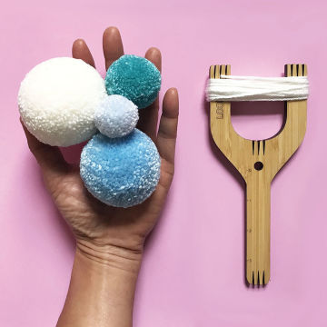 Loome Fiber Craft Tools - Hand holding pompoms with Slingshot Loome Tool