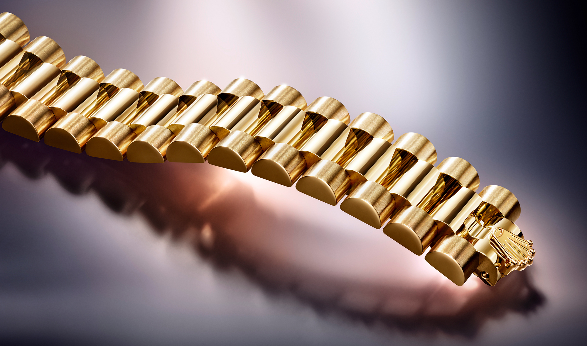 Close-up of a luxury gold wristwatch with a detailed metal link bracelet. The watch face features a classic design with Roman numerals and is partially visible. The background is a clean, white surface with soft lighting highlighting the watch's polished finish.
