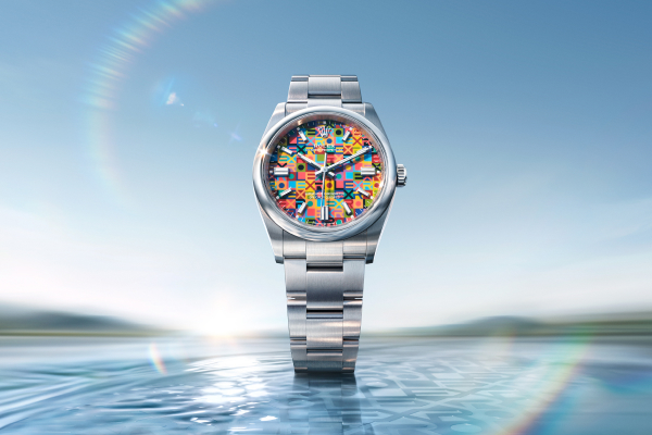 A polished silver wristwatch with a black dial, silver hour markers, and a date display rests against a gradient turquoise background. The watch has a rotating bezel and a stainless steel bracelet. The overall design is sleek and modern.