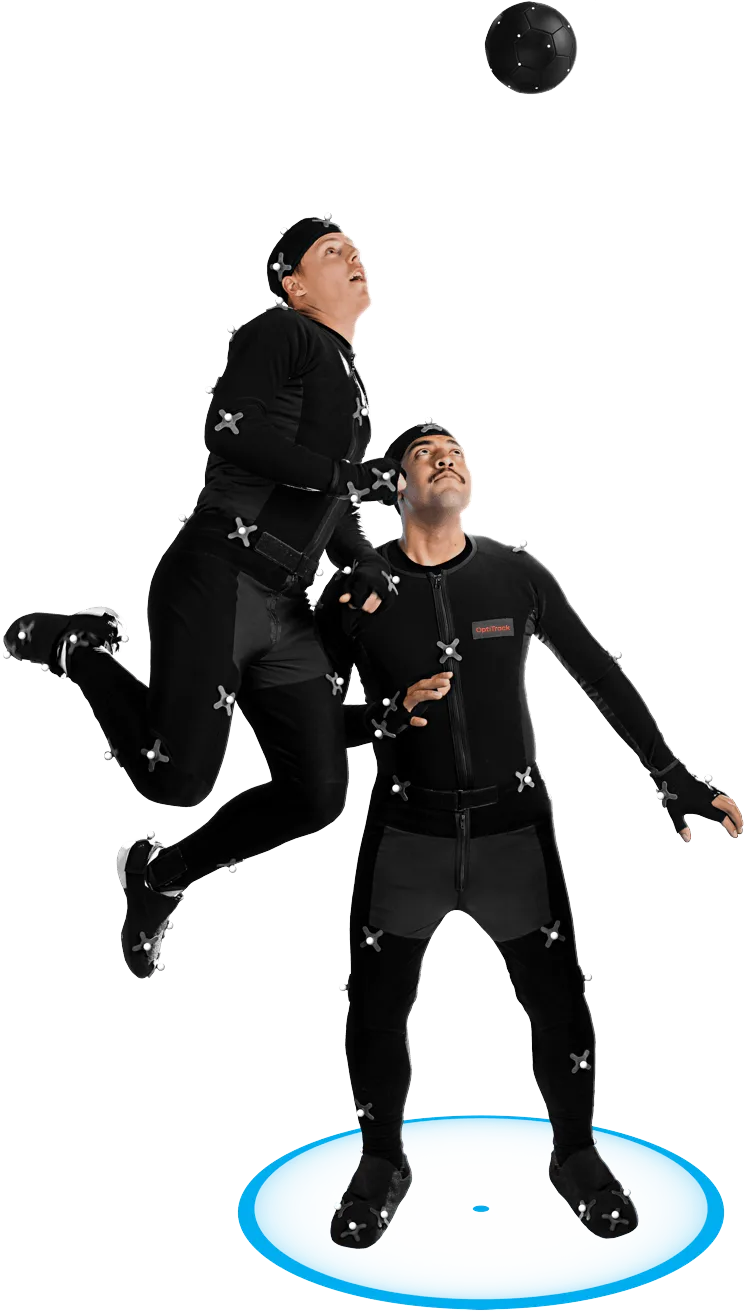 Two men dressed in black motion capture suits simulate a soccer play with one of the individuals leaping to head the ball