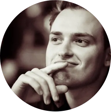 Close-up sepia-toned image of Jamie Kelly, CEO of VRcade. The image is within a circle and he has his index finger resting on his upper chin.