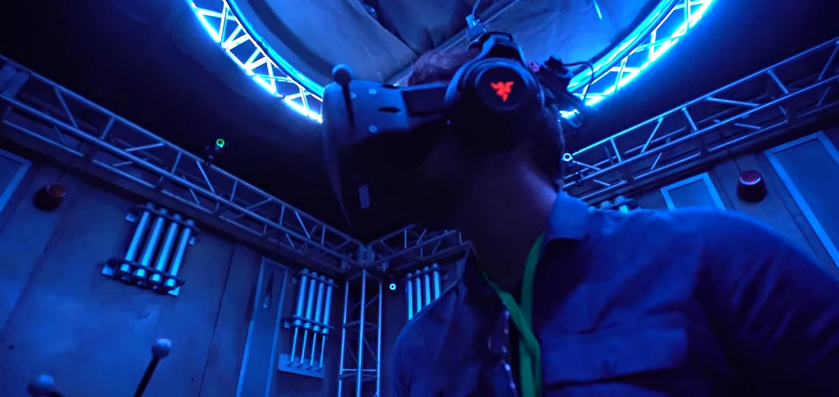 Person standing in a VR "stage" room wearing a full VR headset with blue lights illuminating the room.