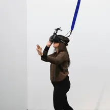 A woman wearing a full virtual reality headset in a room with only white walls