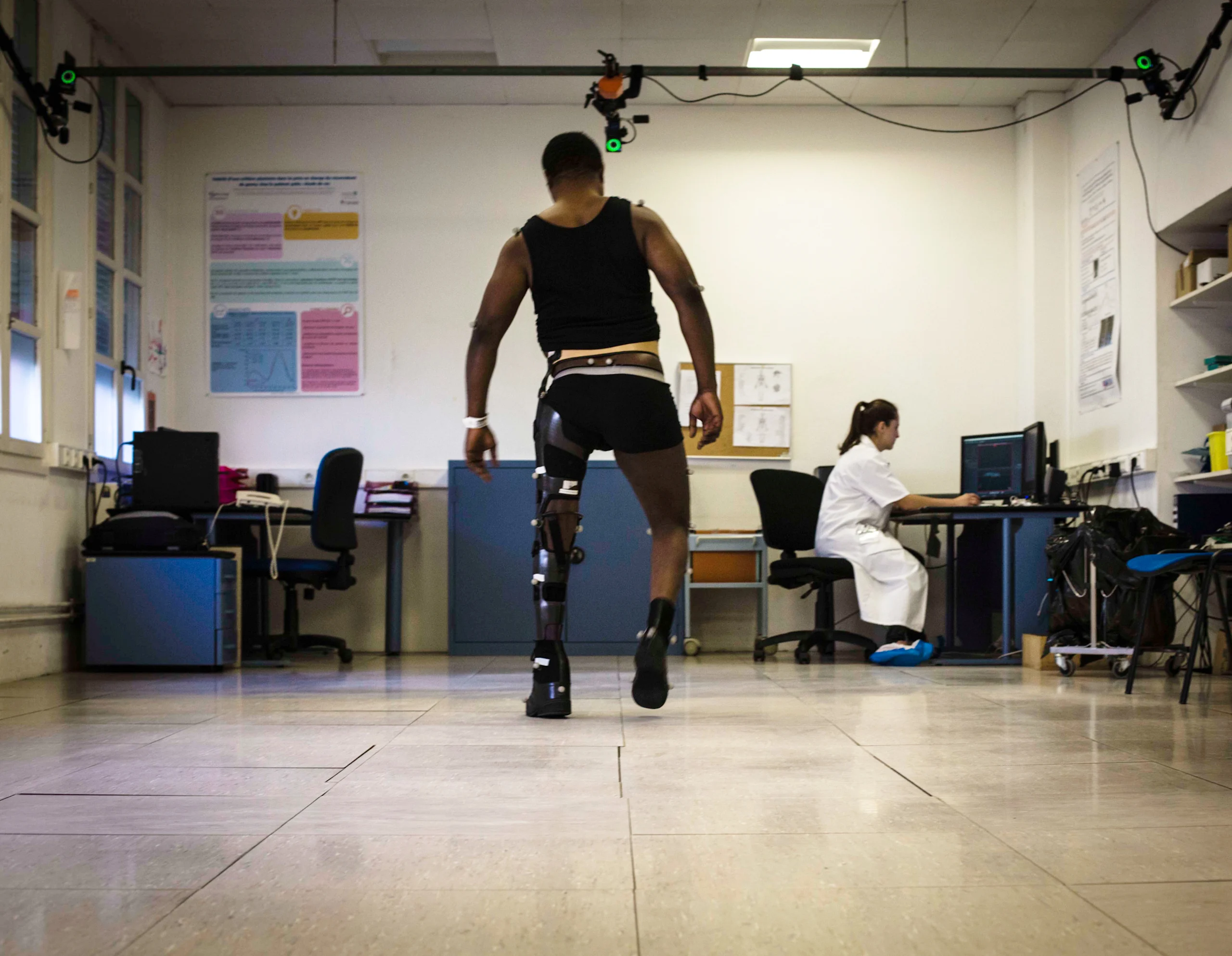 Man walking towards nurse with a brace on his full left leg that includes movement tracking / capture devices