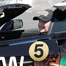 A picture of Sam Schmidt sitting in a convertible car with the top down and the number 5 on the side of the door
