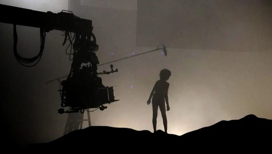 A child in silhouette on a film set standing on a small hill built on a stage