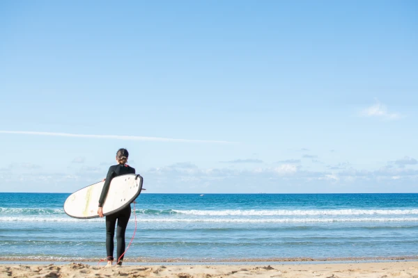 A woman holding a surfboard on a beach