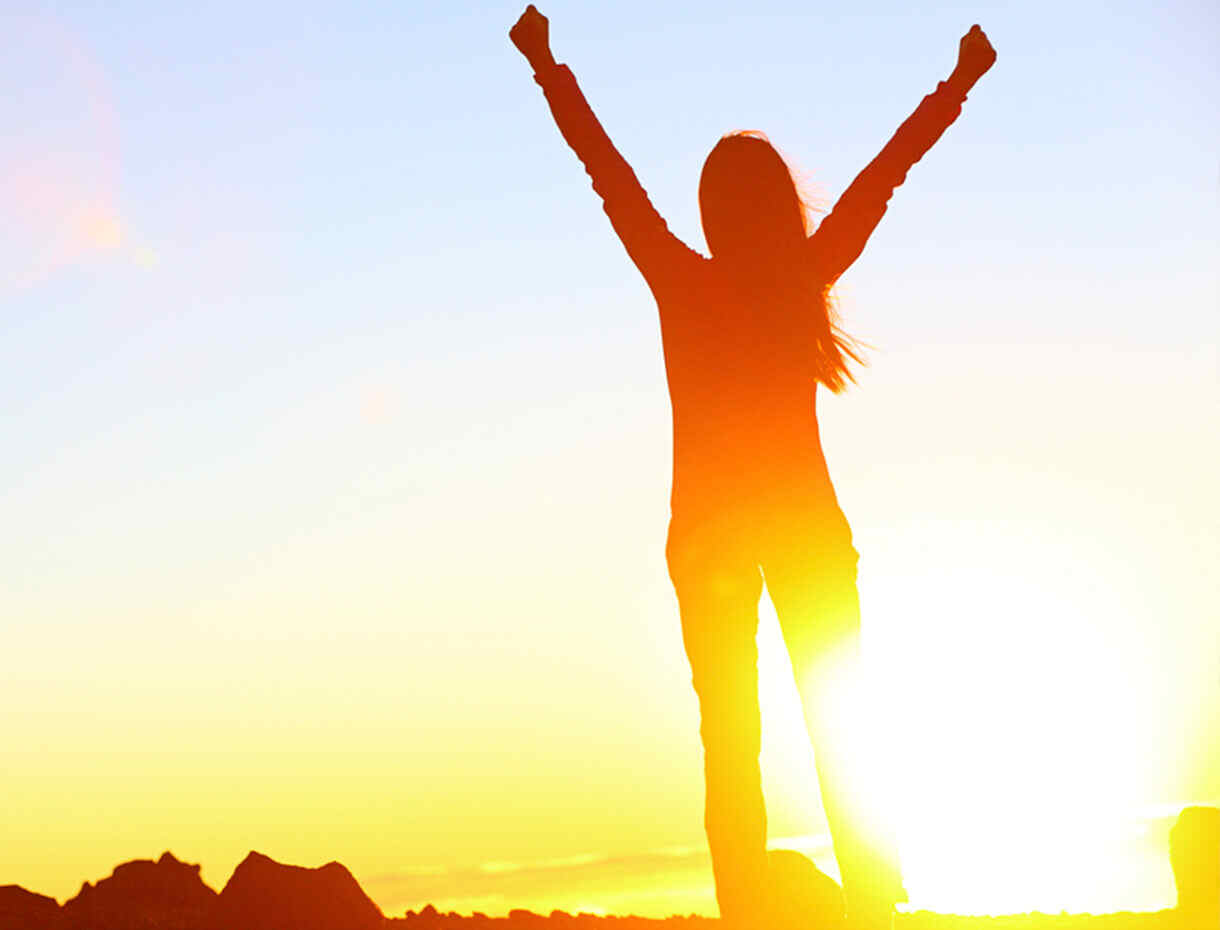 Woman standing in the sun with her arms up