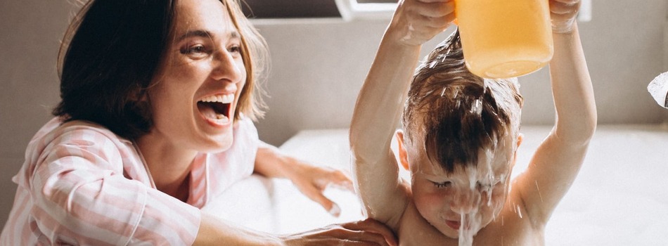 Mother laughing as child throws a cup of water over their head