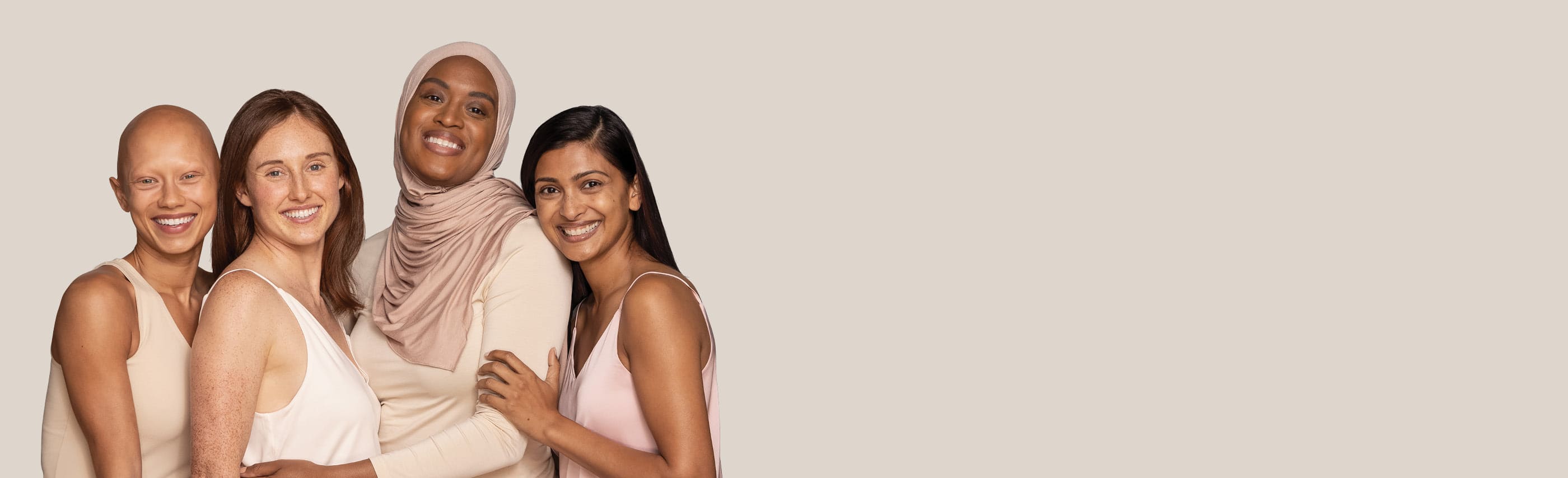 Four women from different ethnicities are standing together and smiling