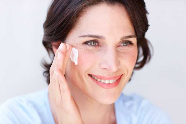 Woman applying NEUTROGENA® moisturizer to face with a cotton pad